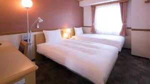 a hotel room with two beds and a window at Toyoko Inn Hitachi Ekimae in Hitachi