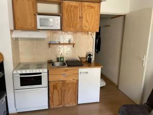 a small kitchen with white appliances and wooden cabinets at Allos, logement pieds des pistes, à 10 minutes de la base de loisirs in Allos