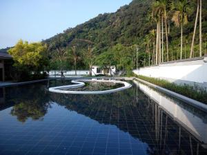 uma piscina de água com palmeiras e uma montanha em 德隆行館 em Yilan City