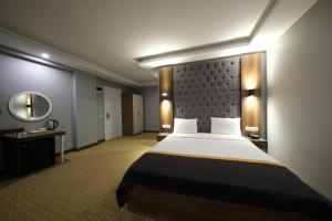 Habitación de hotel con cama grande y espejo en Eniza Hotel, en Mersin