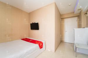 a bedroom with a bed and a tv on the wall at RedLiving Apartemen Bassura City - Gracefull Rooms Tower Dahlia in Jakarta