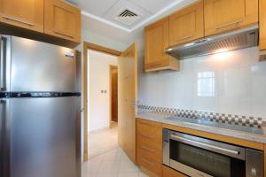 a kitchen with wooden cabinets and a stainless steel refrigerator at Dubai Marina 3 Bedroom Suite with Full Marina View in Dubai