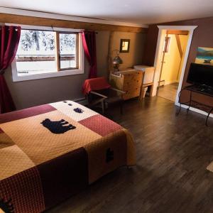 a bedroom with a bed and a desk and a window at Arctic Divide Lodge in Dease Lake