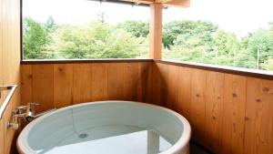a bath tub in a bathroom with a window at HOTORI no HOTEL BAN in Fujikawaguchiko