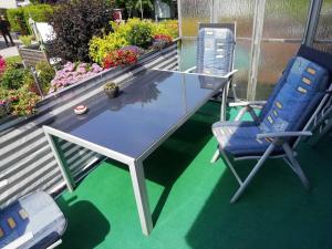a glass table and two chairs on a deck at Ferienwohnung Gartenblick mit Balkon in Maasholm