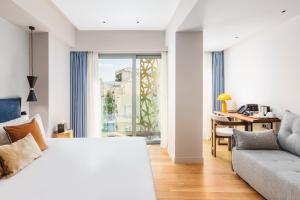 um quarto com uma cama, um sofá e uma janela em The Residence Aiolou Hotel & Spa em Atenas