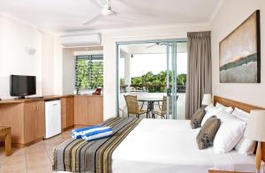 1 dormitorio con 1 cama y cocina con mesa en Mantra in the Village en Port Douglas