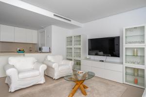 ein Wohnzimmer mit 2 weißen Stühlen und einem TV in der Unterkunft Middel Views flat in El Higueron Ref 64 in Fuengirola