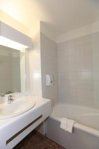 La salle de bains blanche est pourvue d'un lavabo et d'une baignoire. dans l'établissement Hôtel Castellane, à Toulouse