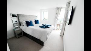 een slaapkamer met een groot bed met blauwe kussens bij Brand New Beachfront Ground floor with garden 2 Bed apartment 6 Guests in Bournemouth