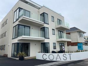 een wit gebouw met een kustbord ervoor bij Brand New Beachfront Ground floor with garden 2 Bed apartment 6 Guests in Bournemouth