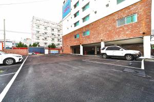 un estacionamiento con dos autos estacionados frente a un edificio en Hotel February Tongyeong Jukrim, en Tongyeong