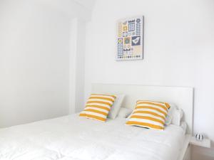 1 cama blanca con 2 almohadas de color naranja y blanco en Apartamento La Zurri near Kursaal, en San Sebastián