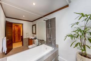 La salle de bains est pourvue d'une baignoire, d'une douche et d'une plante. dans l'établissement Anumana Village Ubud, à Ubud