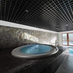 a large tub in a bathroom with a stone wall at C4 Podgrzewany basen sauna, nowy Revist Szklarska in Szklarska Poręba +2 photos