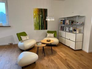 a living room with two chairs and a table and a book shelf at Unsereins Hotel in Bad Steben
