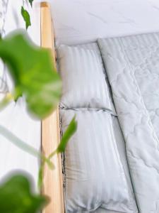 a bed with white sheets and a green plant at Suri's Homestay in Quy Nhon