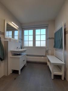 a white bathroom with a sink and a window at Wattschnecke in Bohmstedt