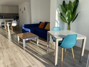a living room with a blue couch and a table and chairs at Canyelles BBQ Apartment in Lloret de Mar