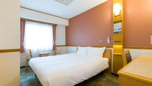 川崎市にある東横INN川崎駅前市役所通の白いベッドとデスクが備わるホテルルームです。