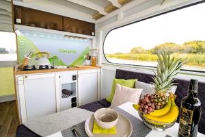 柏林Hausboot FIONA im Yachthafen Berlin-Schmöckwitz auf der Spree und dem Müggelsee von Anfang April bis Ende Oktober的拖车内的厨房和用餐区,配有桌子和一碗水果