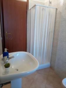 uma casa de banho com um lavatório branco e um chuveiro em Chilù em Cagliari