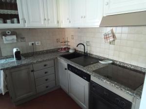 una cocina con armarios blancos y fregadero en Appartamento Loretta, en Marciana Marina