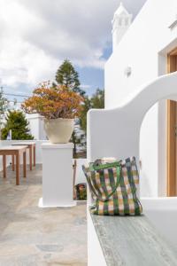 ein weißes Haus mit einer Bank und einer Vase in der Unterkunft Elena Hotel Mykonos in Mykonos Stadt