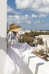 a woman sitting on a ledge drinking a cup of coffee at Elena Hotel Mykonos in Mýkonos City