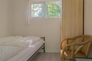 une chambre avec un lit, une fenêtre et une chaise dans l'établissement Zandput 41, à Zoutelande