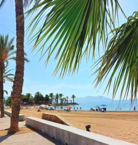 a beach with palm trees and people on the beach at Apartament Claudia II in Puerto de Mazarrón