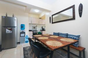 uma cozinha com uma mesa de madeira e um frigorífico em Tropical themed 3BR and DSQ Apartment em Nairobi