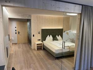 Schlafzimmer mit einem Bett und einer Glaswand in der Unterkunft Vital Hotel Ortlerspitz in Sankt Valentin auf der Haide