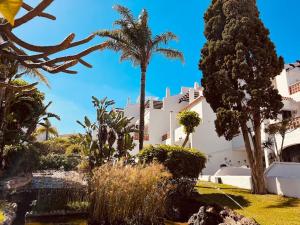 a large white building with palm trees in front of it at Elegant apartment in Amarilla Golf - FW 411 in San Miguel de Abona