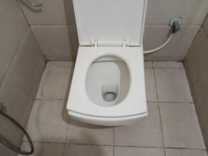 a white toilet in a bathroom with the seat up at PRIDE MANYATA in Bangalore