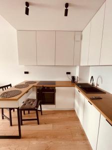 a kitchen with white cabinets and a table and a sink at Apartament na Okrzei in Sandomierz +7 photos