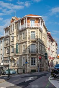 Un grand bâtiment en pierre avec un balcon se trouve dans une rue. dans l'établissement Ama Hôtel, à Biarritz