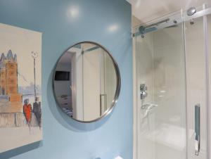 a bathroom with a round mirror on the wall at Ty Glyn in Criccieth +28 photos