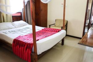 a bedroom with a bed with a red blanket on it at Darajani Hotel in Mombasa