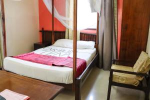 Darajani Hotel في مومباسا: غرفة نوم بسرير وطاولة وكرسي