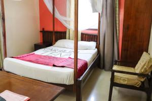 a bedroom with a bed and a table and a chair at Darajani Hotel in Mombasa