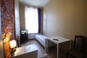 Cette chambre comprend un lit, une table et une fenêtre. dans l'établissement Vanilla Hostel Wrocław, à Wrocław