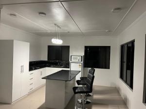 a kitchen with white cabinets and a black counter top at Bula Homestay in Labasa