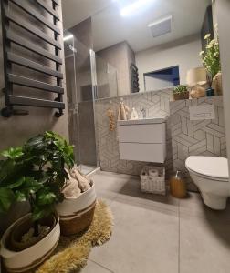 a bathroom with a toilet and a sink and plants at Posnania Comfort Apartment, free parking, self check-in 24h in Poznań