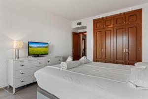 een witte slaapkamer met 2 bedden en een televisie bij Marysol beachclose apartment with pool Ref 200 in Benalmádena