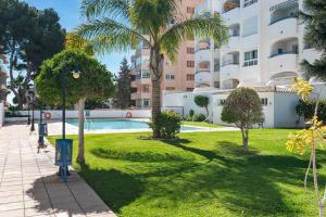 een park met een zwembad en palmbomen en een gebouw bij Marysol beachclose apartment with pool Ref 200 in Benalmádena