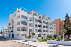 een wit gebouw met palmbomen ervoor bij Marysol beachclose apartment with pool Ref 200 in Benalmádena