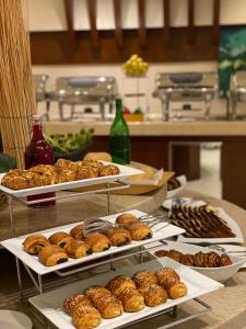 uma mesa com bandejas de donuts e outros produtos de pastelaria em Sumou Al Khobar Hotel em Al Khobar