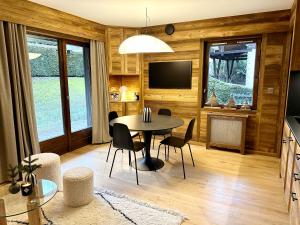 een eetkamer met een tafel, stoelen en een tv bij Megève Rochebrune, superbe appartement avec jardin in Megève