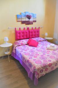 1 dormitorio con 1 cama rosa y 2 mesas en Casa di Osio - Porta Romana, en Siena